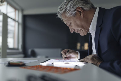 Senior businessman drawing on shining tablet