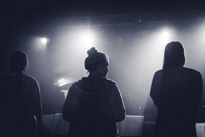 Silhouette women standing next to stage light