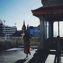 Man standing outside temple against sky in city