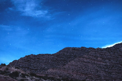 Low angle view of mountain range against cloudy sky