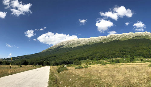 Road amidst field against sky