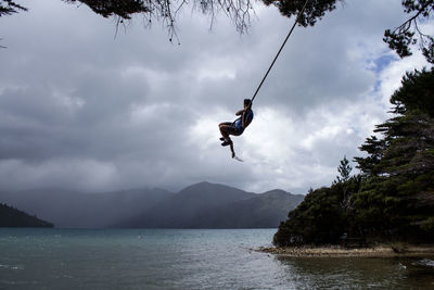 Person paragliding in water against sky