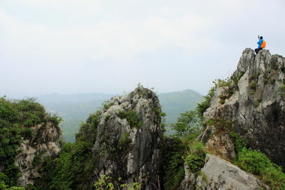Panoramic view of people on cliff against sky