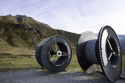 Large spools on field against sky