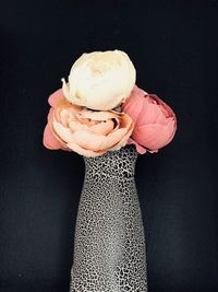 Close-up of hand holding ice cream against black background