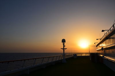 Street by sea against sky during sunset