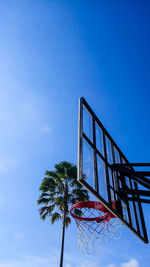 The basketball rim and tree in the blue sky