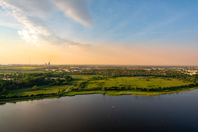 Scenic view of river amidst field against sky at sunset