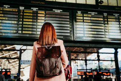 Rear view of woman wearing backpack standing on railroad station