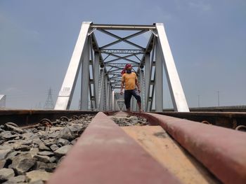 Low angle view of man standing on bridge against sky