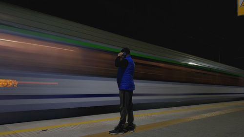 Man talking on smart phone while standing at railroad station platform