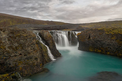 Scenic view of waterfall against sky