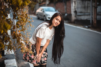 Portrait of smiling young woman standing against tree during autumn