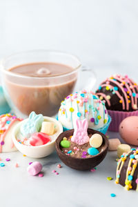 Hot chocolate bombs decorated for easter with a glass cup of hot cocoa in behind