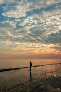 A boy standing on the beach witnessing the epic sunset