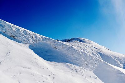 Snow covered mountain against blue sky