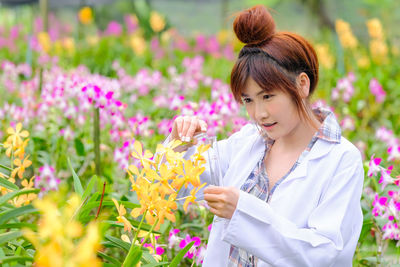Beautiful woman standing by flowering plants