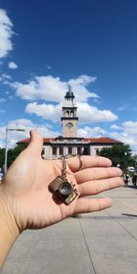 Cropped image of person holding clock tower against sky