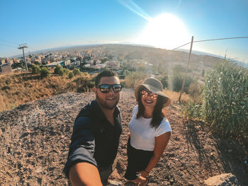 Portrait of smiling young man and woman against sky