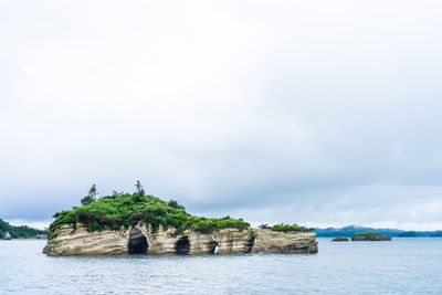 Scenic view of rocks by sea against sky