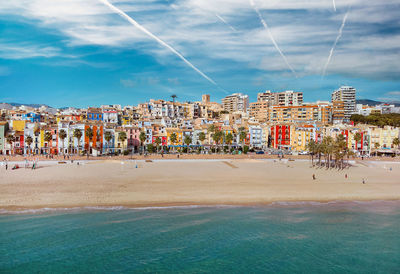 Scenic view of beach by buildings against blue sky