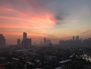 Buildings in city against romantic sky at sunset