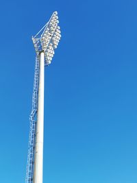 Low angle view of ferris wheel by building against clear blue sky