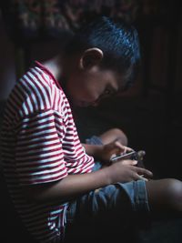 Boy playing game in mobile phone at home