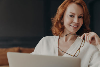 Portrait of smiling businesswoman using laptop at home