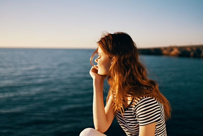 Beautiful woman against sea at sunset