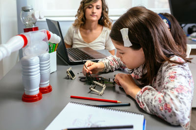 Female student connecting wire on electrical circuit in robotics class