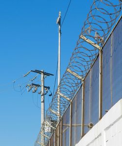 Low angle view of barbed wire against clear blue sky