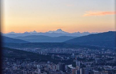 Aerial view of townscape and mountains against sky