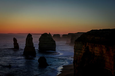 Rocks on sea against sky during sunset