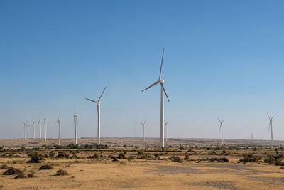 Wind turbines on field against clear sky