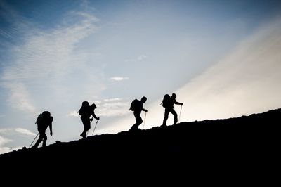 Silhouette people hiking on mountain against sky