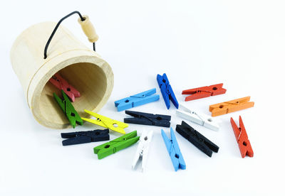 Multi colored clothespins and bucket over white background