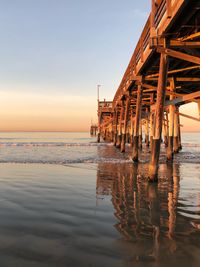 Pier on sea against sky at sunset