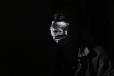 Portrait of a man wearing a mask with a hopeful expression on a black background