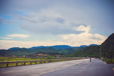 Road leading towards mountain range against sky