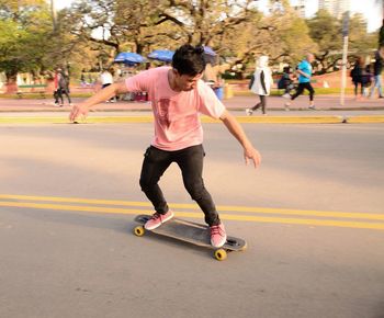 Full length of boy skateboarding on road