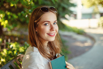 Portrait of beautiful young woman reading book while sitting in park