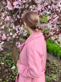 Low section of woman standing on pink cherry blossom