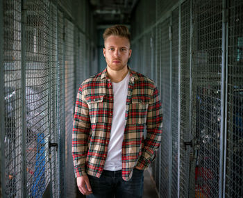 Portrait of young man standing against fence