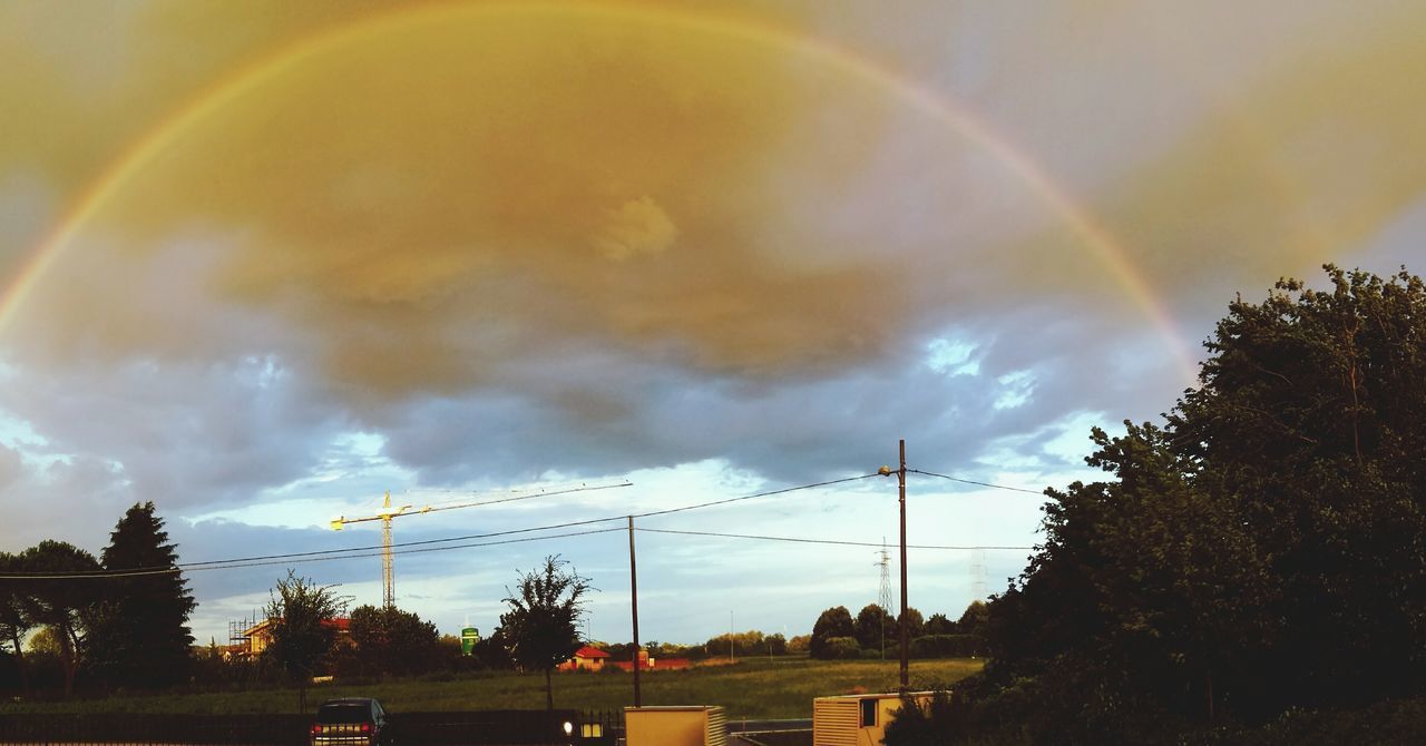 rainbow, tree, multi colored, scenics, beauty in nature, landscape, tranquil scene, majestic, nature, tranquility, day, sky, cloud - sky, power line, natural phenomenon, cloudy, power supply, no people, atmospheric mood