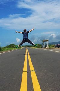 Man jumping on road against sky