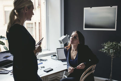 Female colleagues discussing by desk at home office