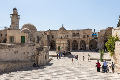 People in front of historical building against clear sky