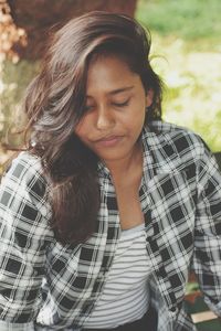 Young woman looking down while standing outdoors