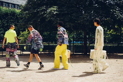 Rear view of people walking on road against trees